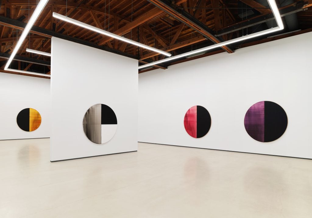 Installation view inside Sean Kelly Los Angeles gallery space with wood beam ceiling and four color field tondo paintings on the walls.