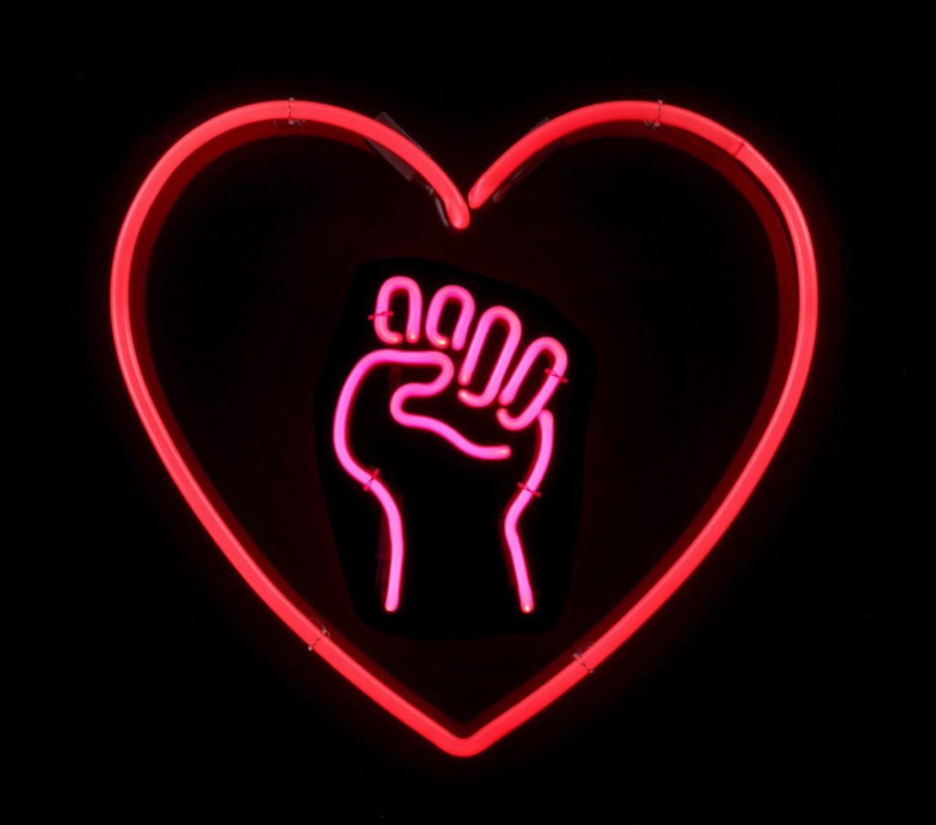 an artwork by Michele Pred titled Love as Activism is made of neon red heart surrounding a pink fist