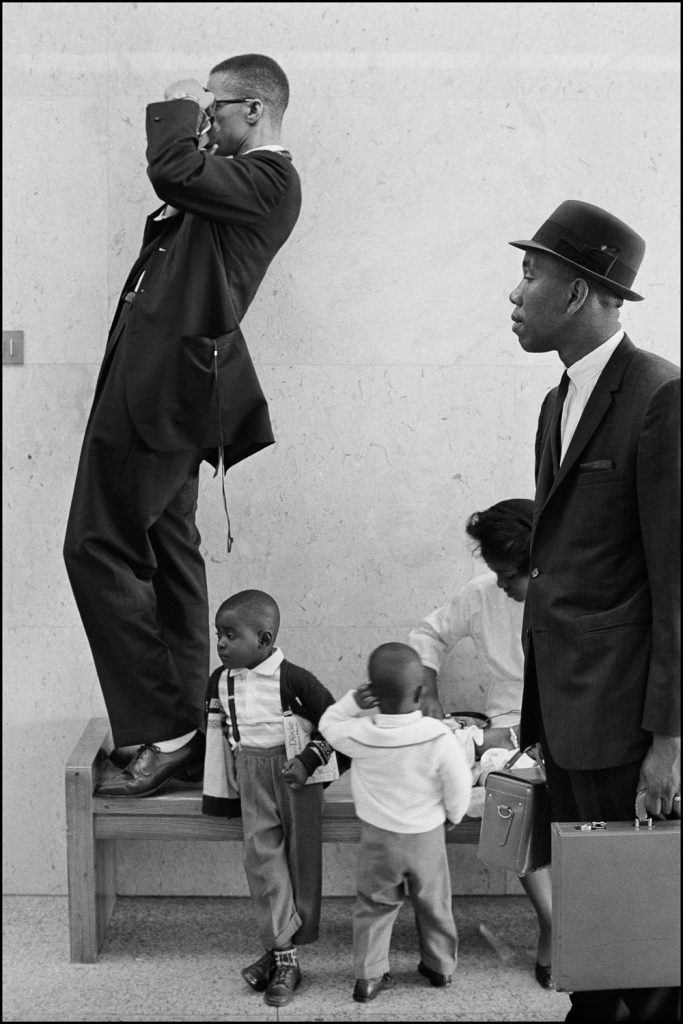 a black and white photograph depicting two Black men dressed in suits with two small children, also wearing dress pants and shirts.