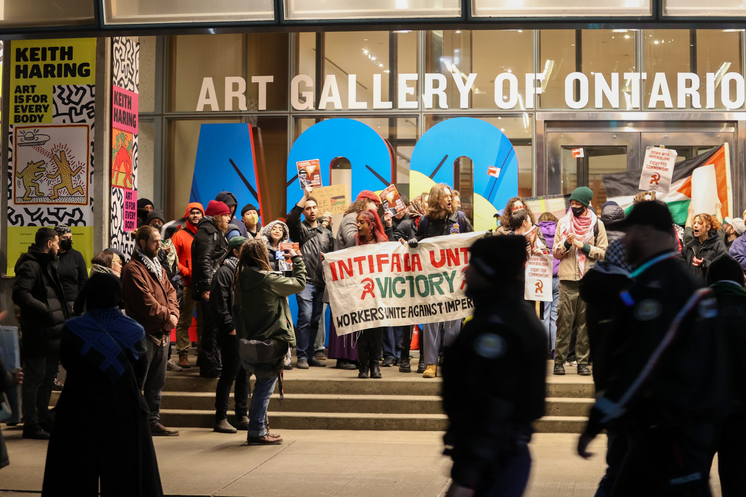 Protestors stand outside of a museum holding signs in support of Palestine