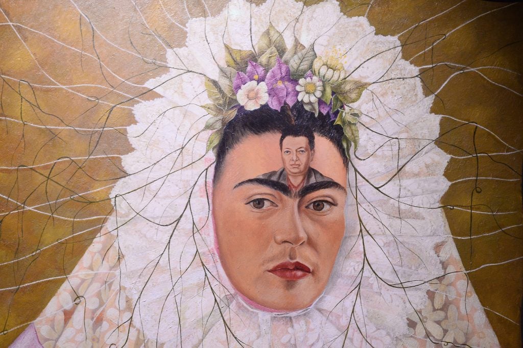 Detail from a self-portrait by Mexican painter Frida Kahlo, her head crowned with flowers and her forehead drawn with a picture of a man, her husband Diego Rivera.