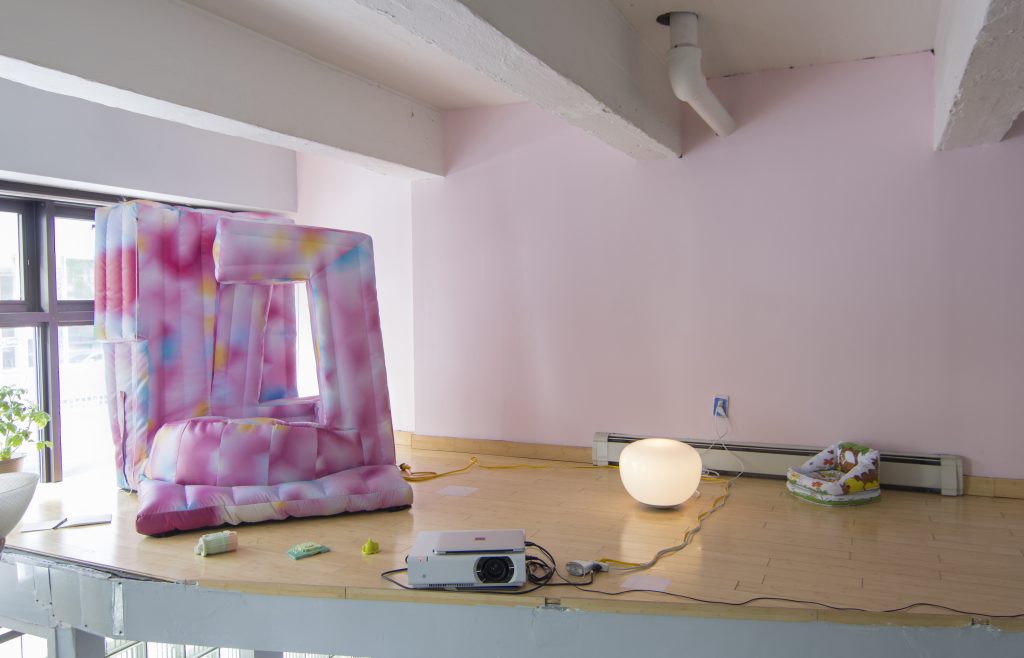 a pink and white inflatable object in a gallery space.