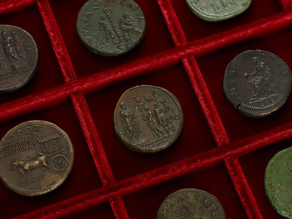Selection of ancient coins in a red display case.