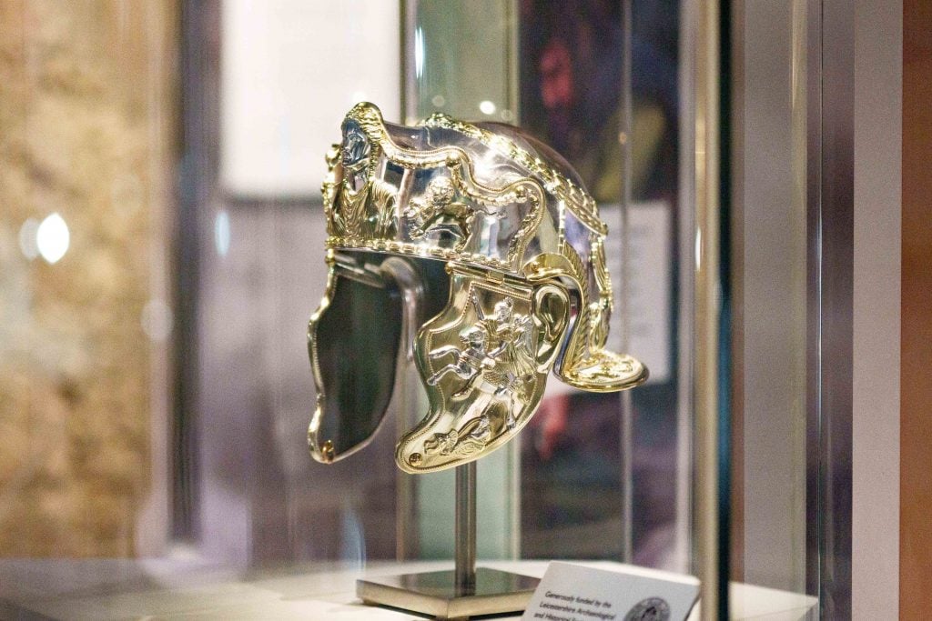  gold-coloured 3D printed replica of an ancient Roman helmet in a display case