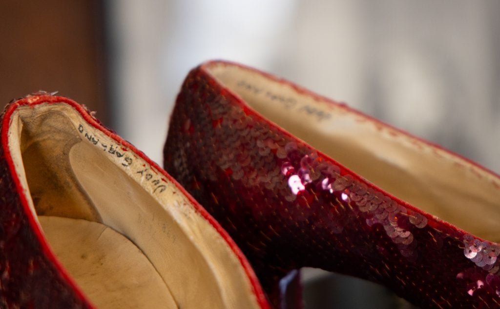 Close up of a pair of sequined shoes, the inside lining of which reads "Judy Garland."