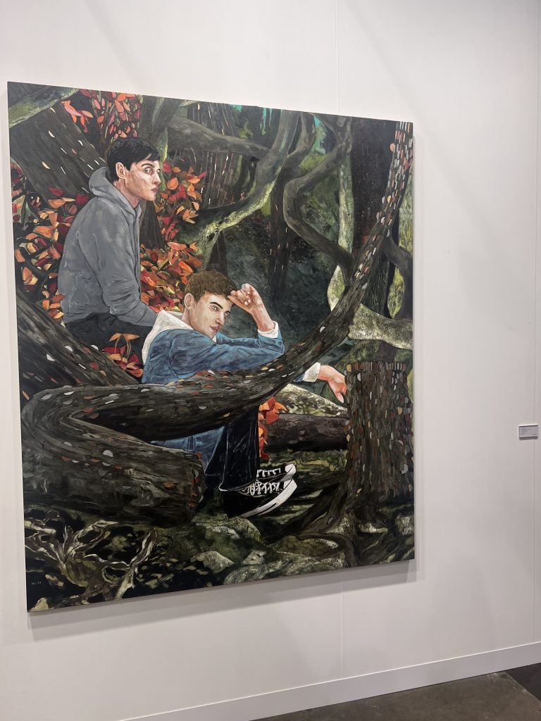 a painting depicts two young men in hoodies seated amongst flora 
