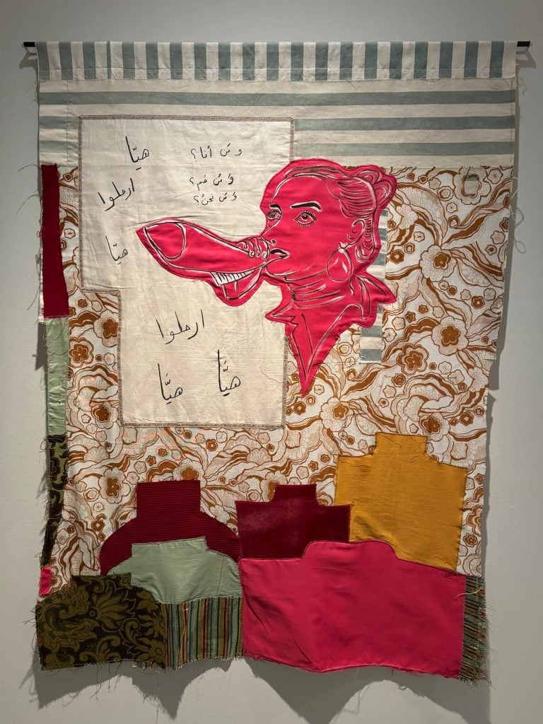 a textile quilt with a woman speaking on it