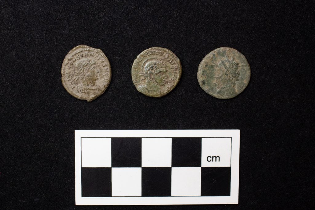 Three ancient Roman coins against a black background.