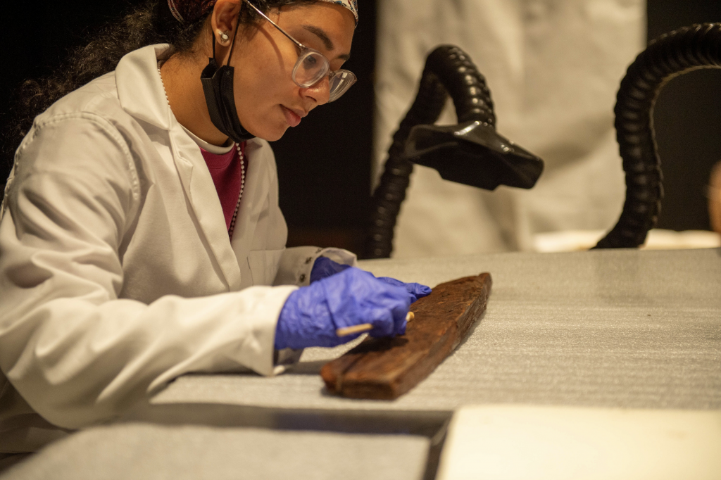 A conservator at work on a plank of wood from an ancient Egyptian boat.
