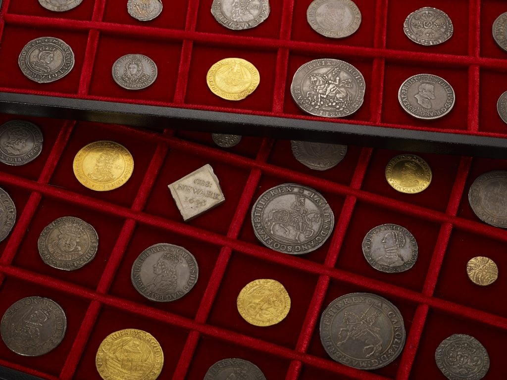 Selection of antique coins in a red display case.