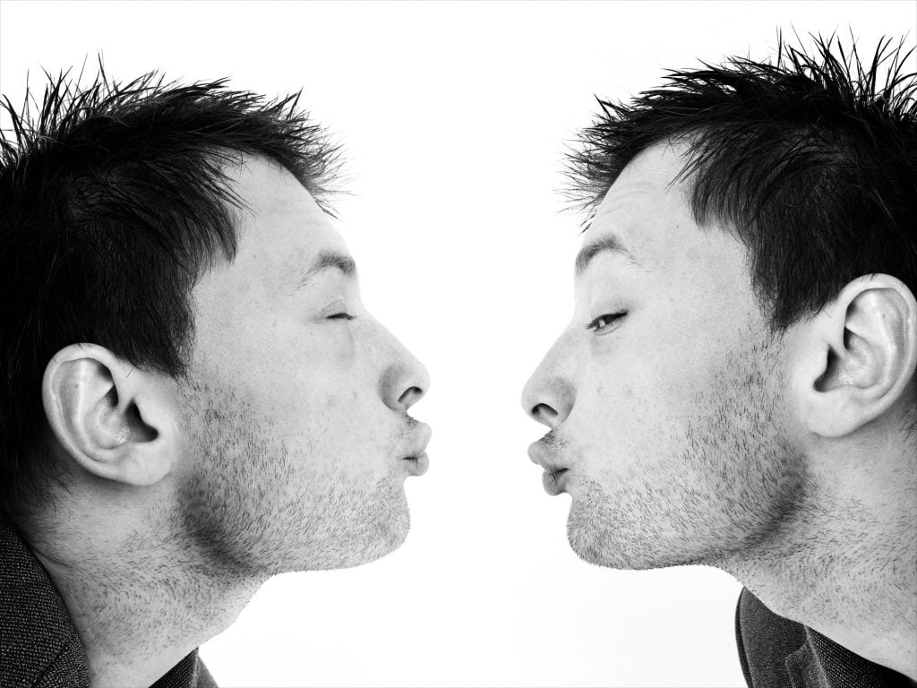 a man appearing to lean in from both sides of picture frame andand kiss himself