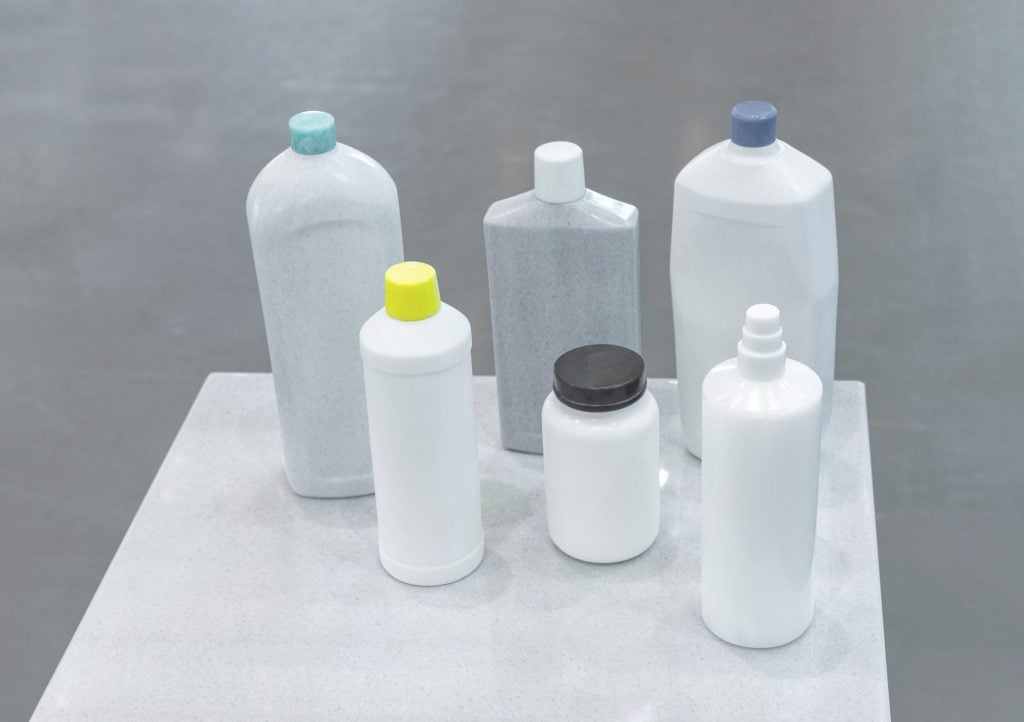 Six various size and shaped bottles that appear to be regular household plastic bottles but are in fact made out of stone.