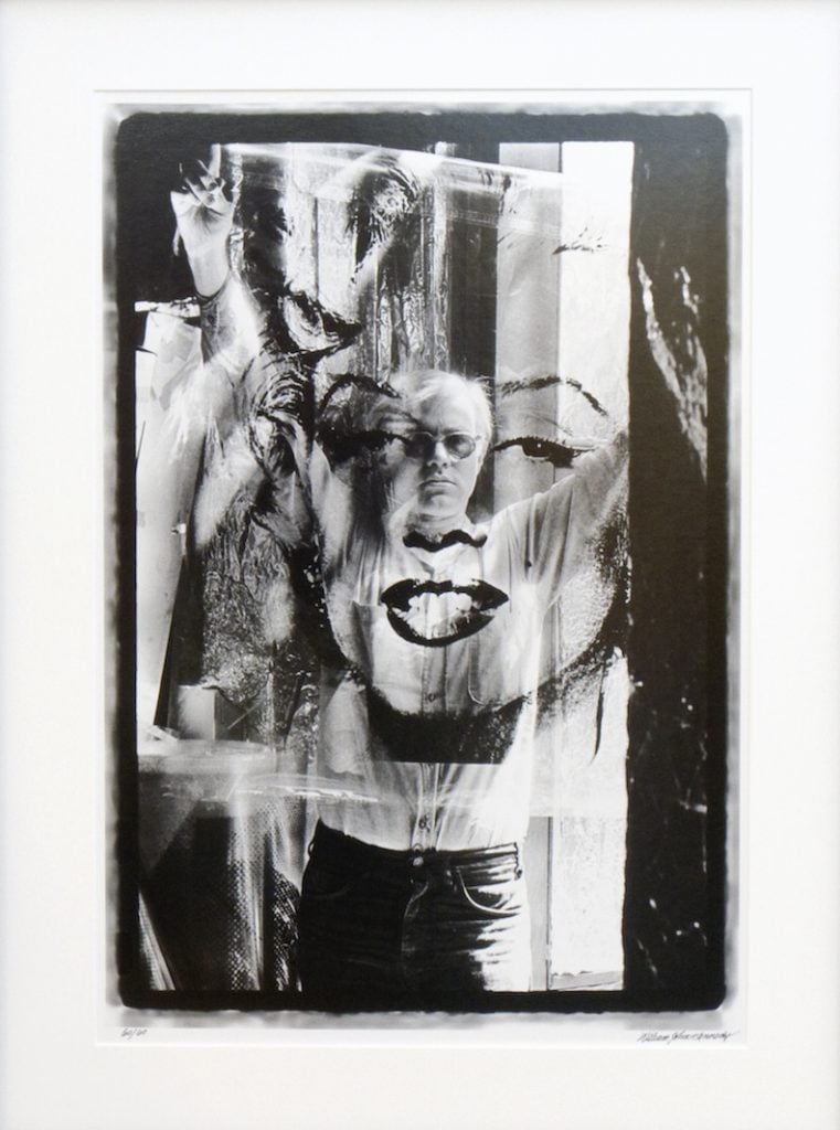 Artist Andy Warhol poses with an image of Marilyn Monroe.