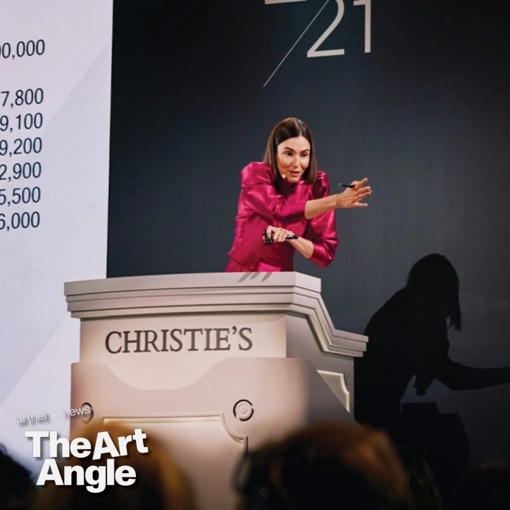 a female auctioneer leans against the rostrum to take a bid