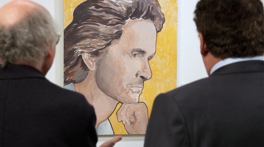 Two men, seen from the back, looking at a portrait depicting a young man, his hair combed back, his fist against his chin.