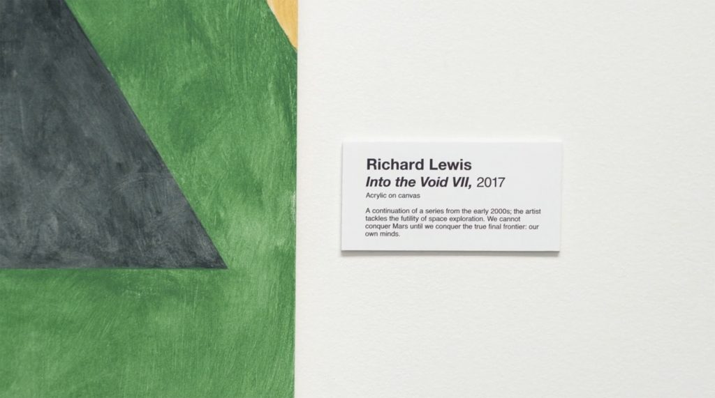 Wall text in a gallery that reads "Richard Lewis, Into the Void, 2017... We cannot conquer Mars until we conquer the true final frontier: our minds."