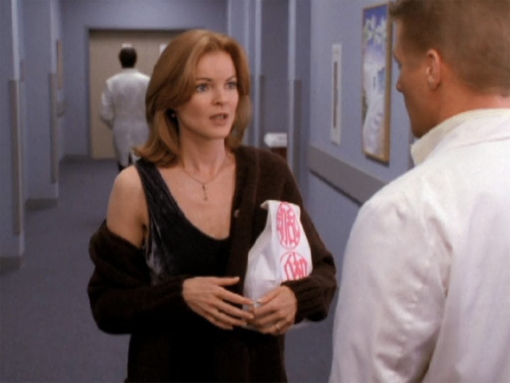 A woman holding a white paper bag printed with a red motif.