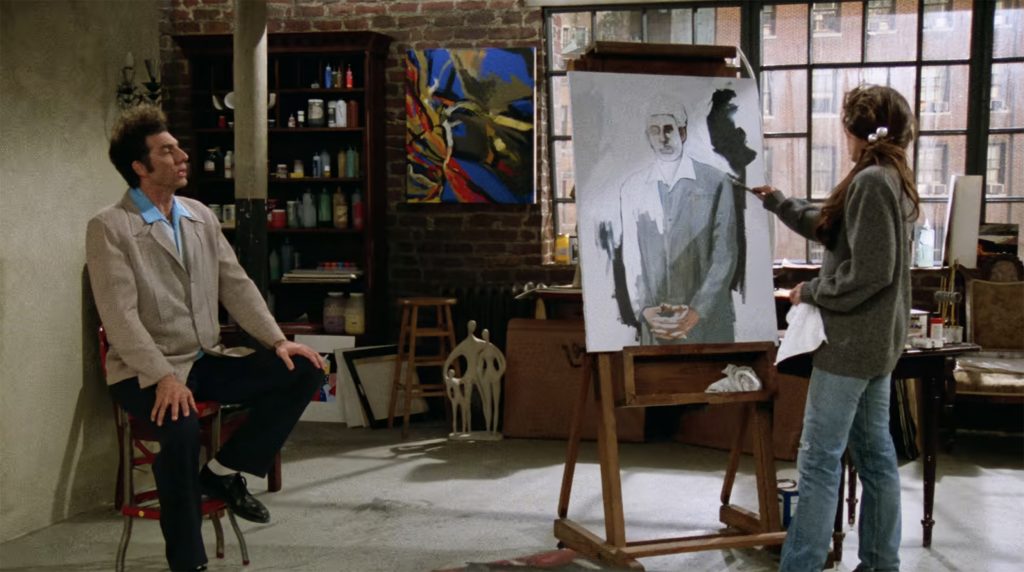 A woman at an easel painting a portrait of a man, who is posing for her on a stool.