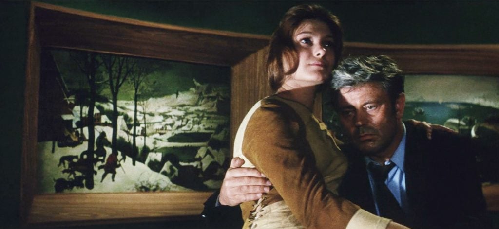 A still from the film Solaris, depicting a man and woman embracing, while a snowy landscape hangs behind them.
