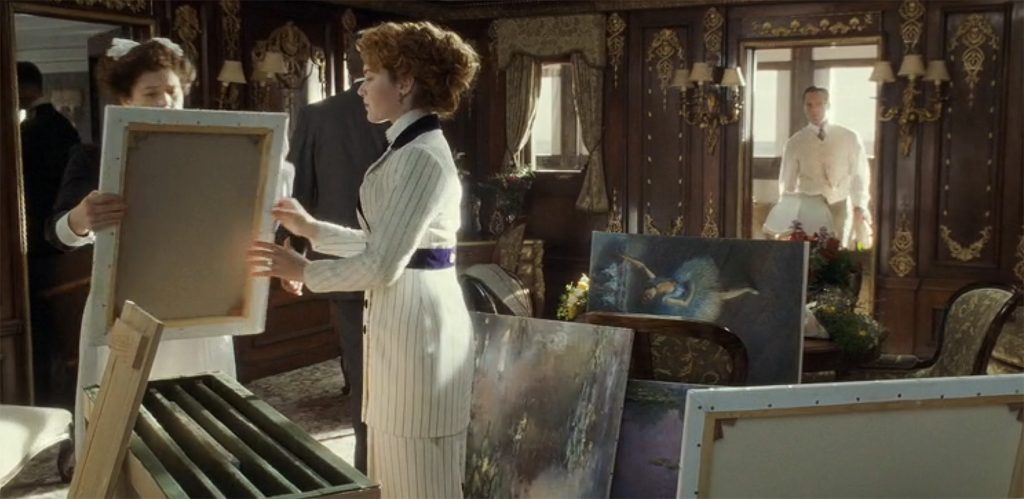 A woman is being passed a canvas, while standing in a room of paintings by Picasso and Degas, in a scene from the film Titanic.
