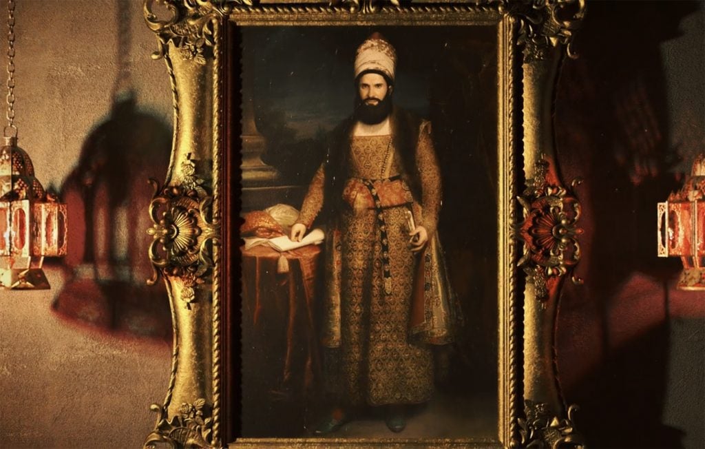 A portrait of a man, dressed in an extravagant Persian ensemble, hanging between two lamps.