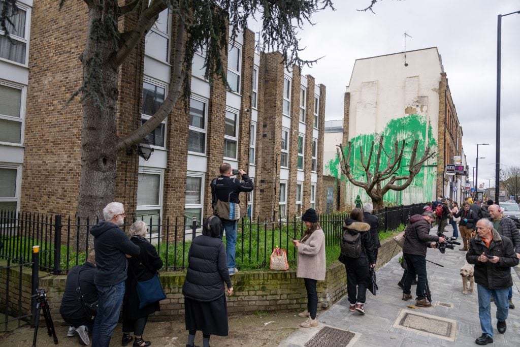 People photograph the new Banksy mural in London.