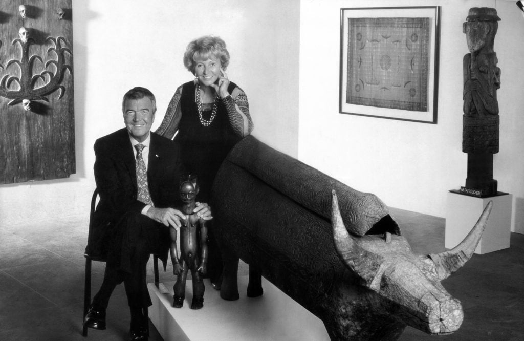 Black and white image of glamorous collectors Monique and Jean Paul Barbier-Mueller with some of their African tribal art pieces.