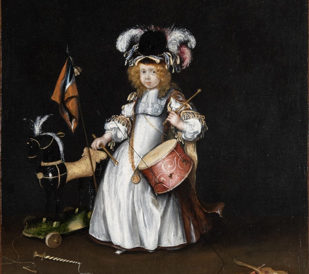 a small elaborately dressed child with a rocking horse toy