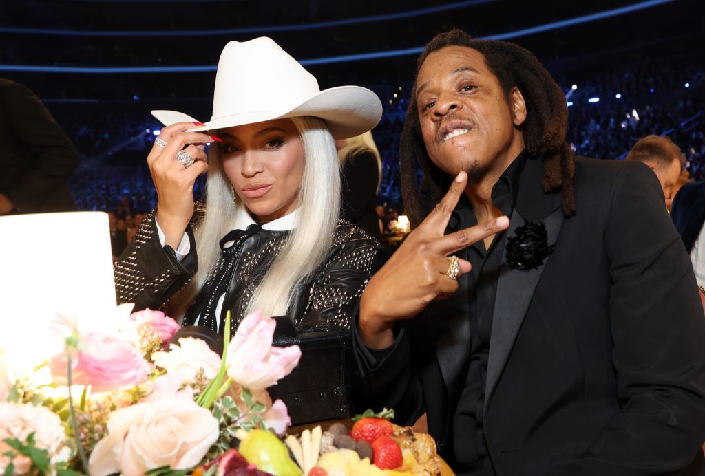 A woman, pop singer Beyoncé, in a cowboy hat and a man, her husband Jay-Z, seated at a table