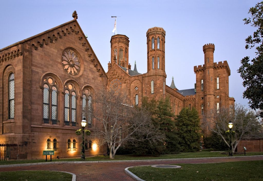The image is a photo of a large brick building with a several towers. It is known as the Smithsonian Institution Building, also called 