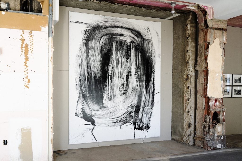 A large abstract artwork hangs in a raw, vacant office space.