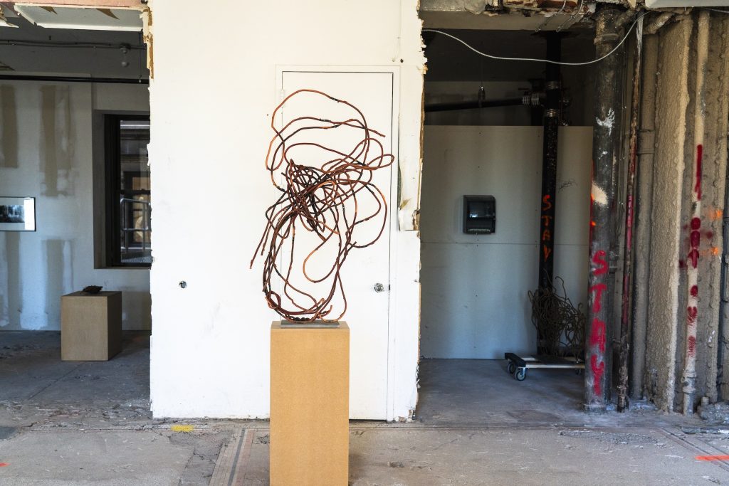 A metal sculpture in a raw, vacant office space.