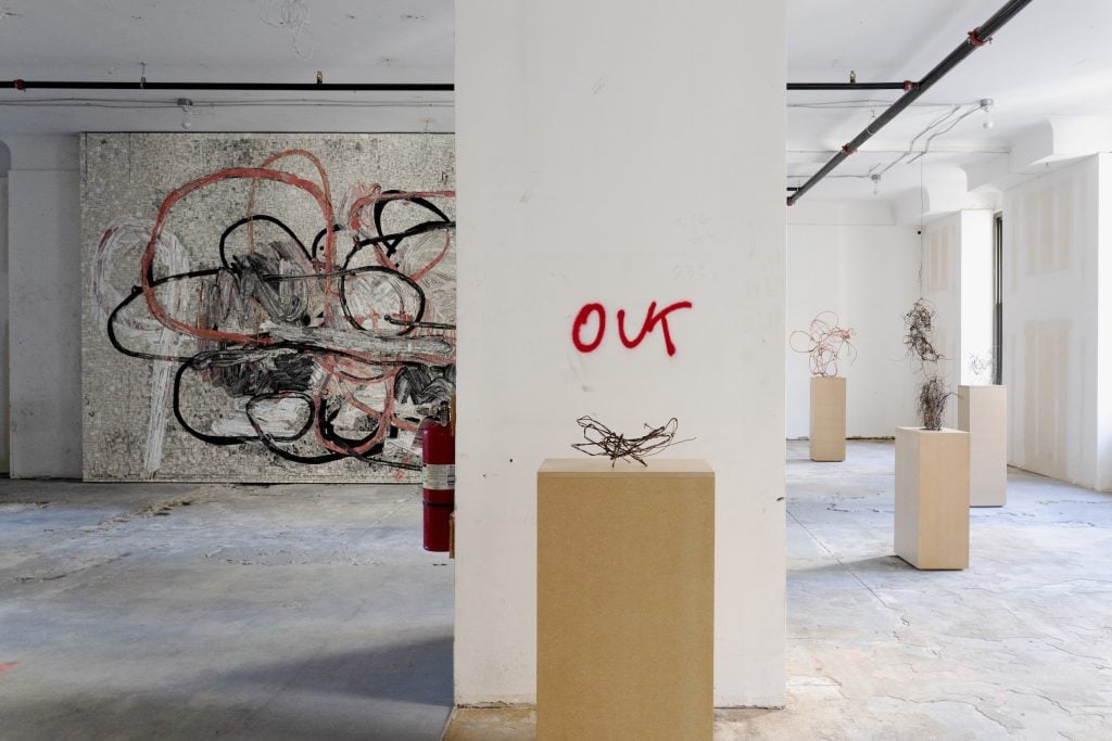 Artworks hang in a raw, vacant office space.