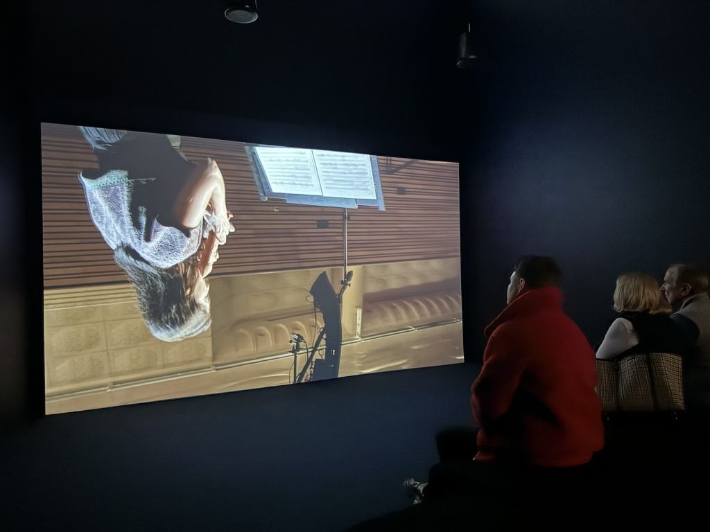 A person watches a video of a woman playing a musical instrument that is projected upside-down