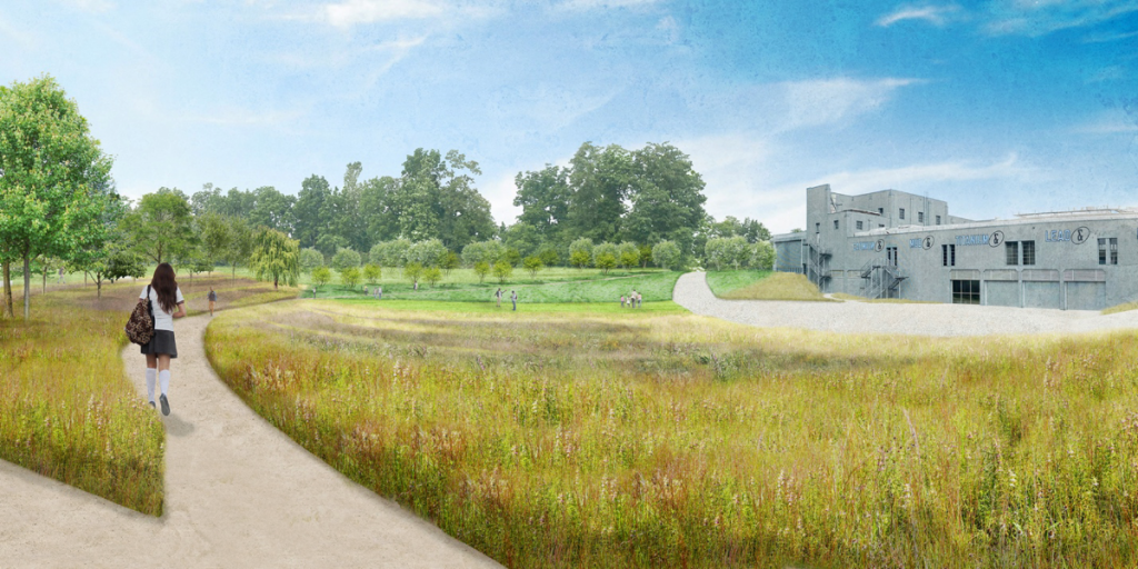 This image appears to be an artist's rendering of a landscape design for a park or a green space near an institutional building. On the left side of the image, a pathway meanders through a field of tall grasses and wildflowers, flanked by young trees and patches of green grass. There are several people in the distance, casually enjoying the space—some are walking and others are seated on the grass. A woman with long hair, wearing a short-sleeve dress and carrying a large bag on her shoulder, is walking along the path, leading the viewer's eye through the scene. She seems to be heading toward a large industrial-style building on the right side of the rendering, which is made of concrete or metal and has a relatively flat facade with square windows. The building is adorned with letters spelling out 
