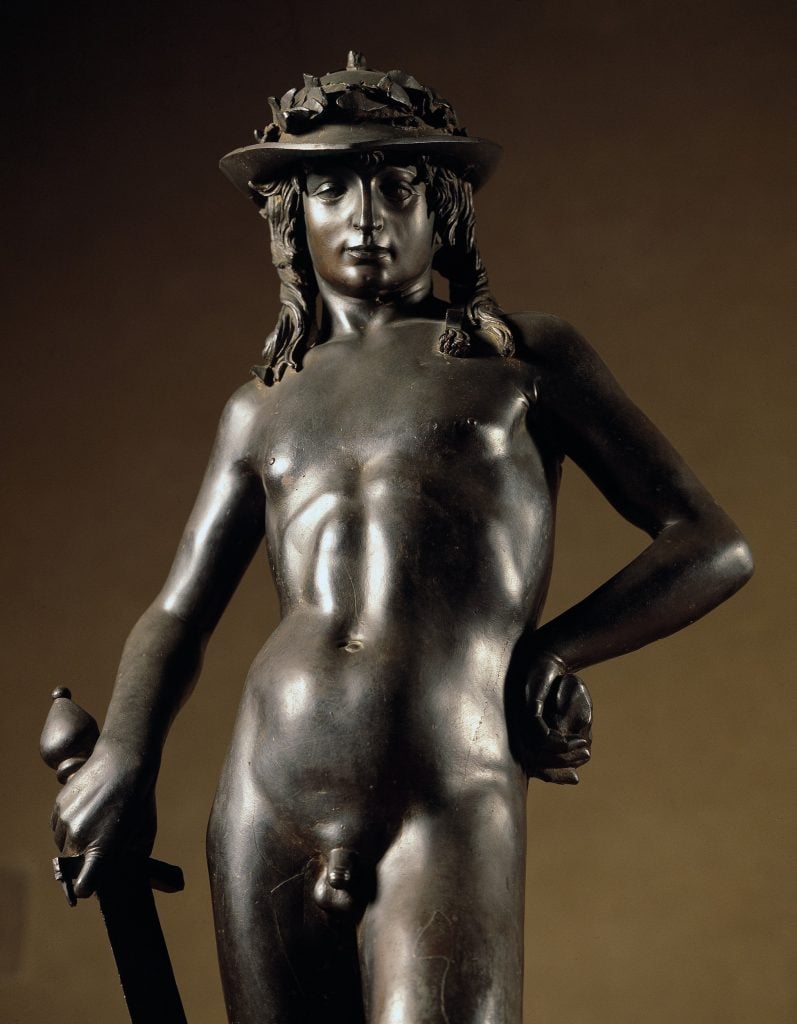 Detail of Donatello's bronze sculpture David, depicting a nude young man with long hair, in a helmet, and clutching a sword.