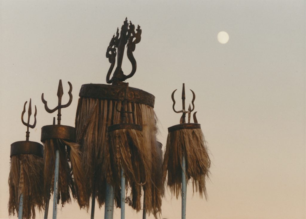 A group of warrior banners, with a pitchfork and horsehair, seen against a dusky sky.