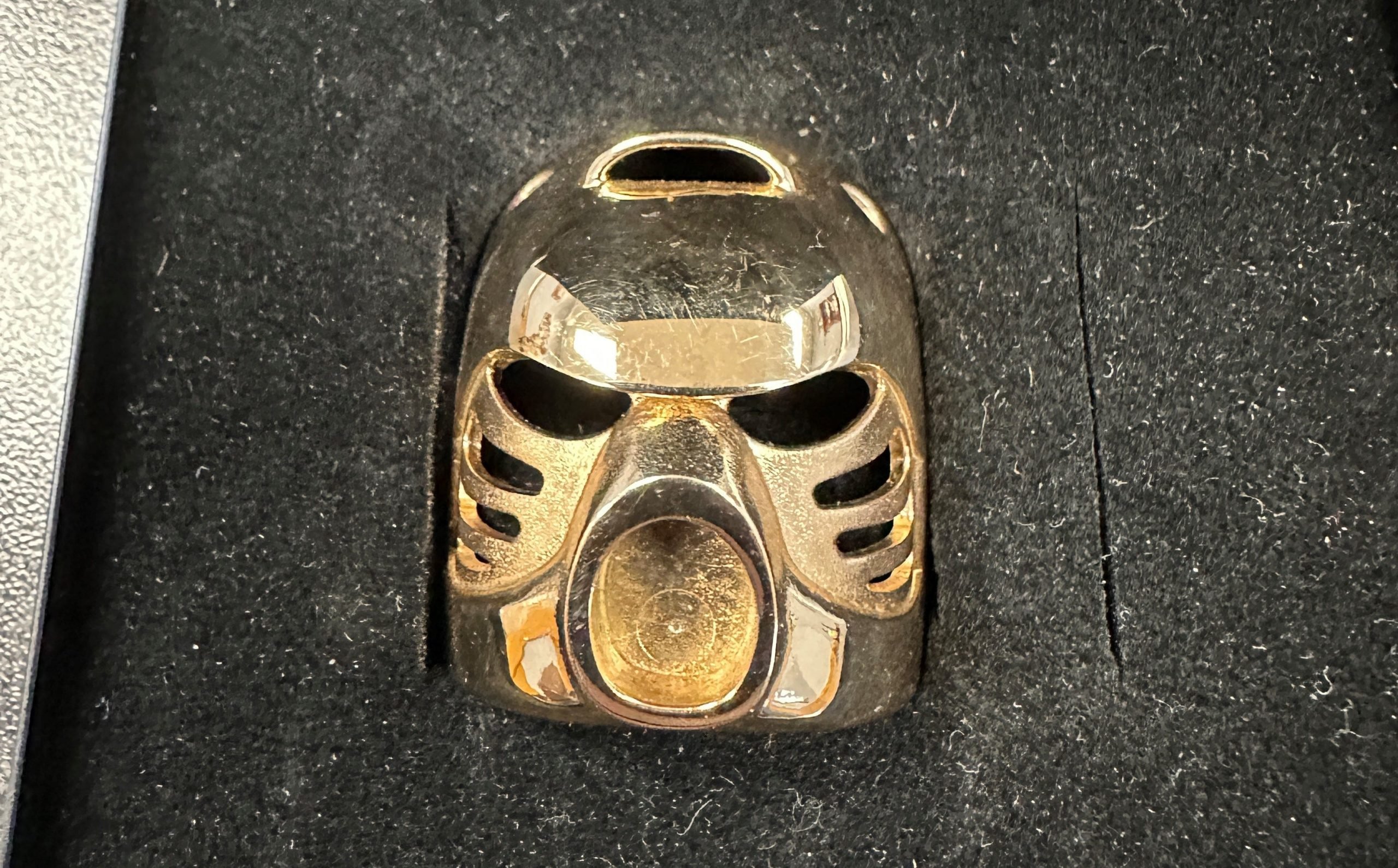 A rare, 14-karat gold Lego piece shaped like a mask.