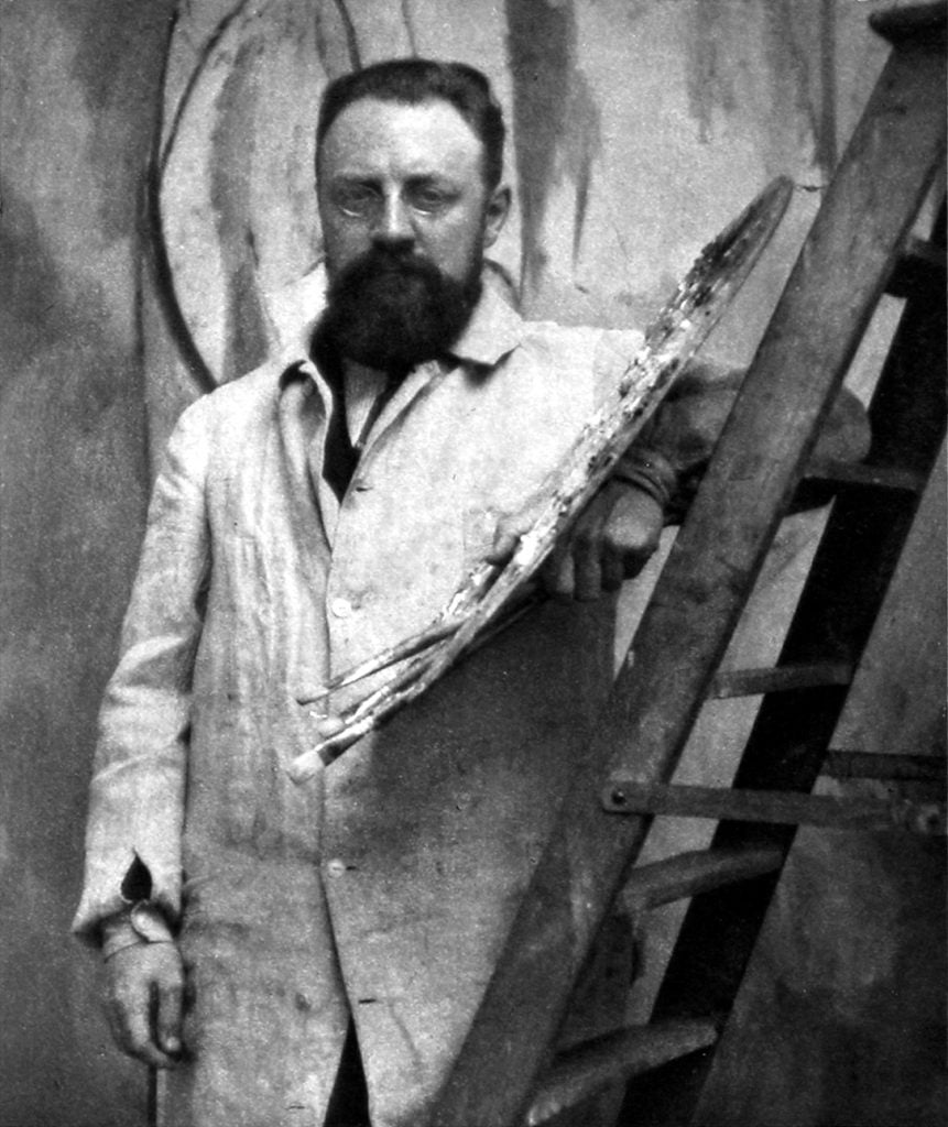 An artist at his easel in a smock.