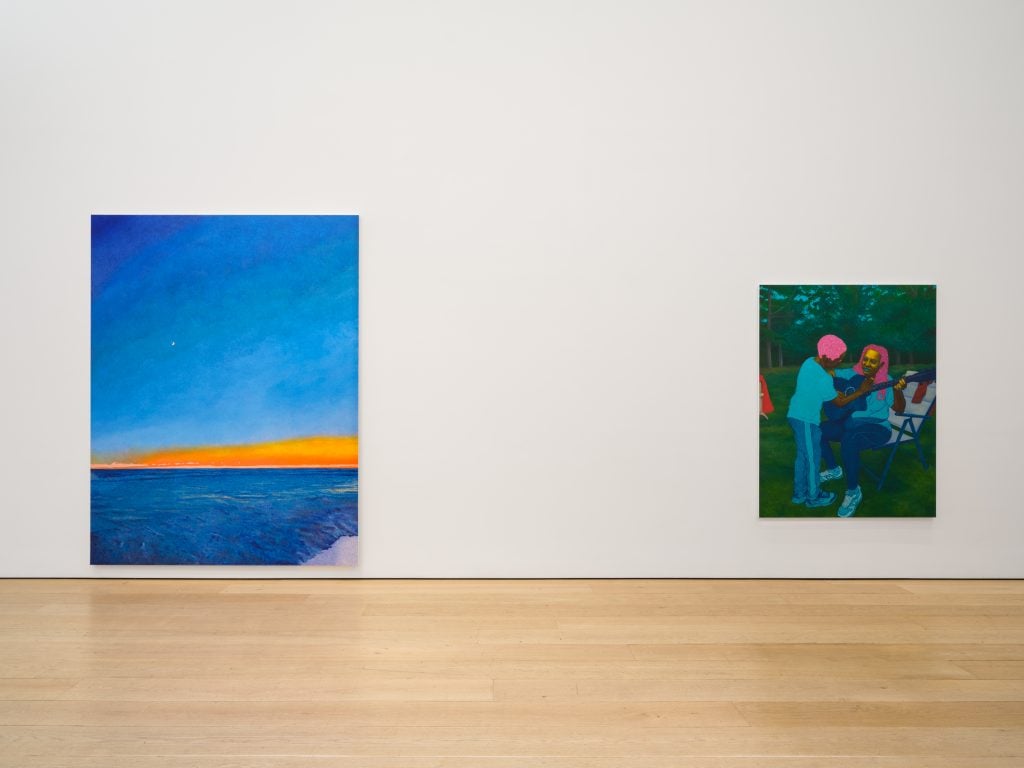 Installation view with two paintings, one seashore landscape on the left and a portrait of a mother with child playing with a guitar on the right.