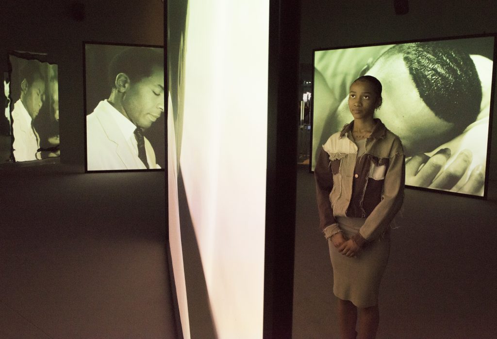 girl stands among screens showing video art
