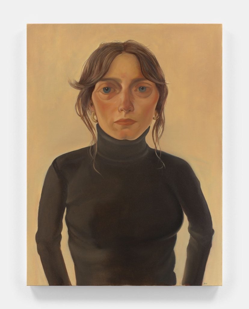 Portrait of a woman named Ally wearing a black turtleneck with brown hair pulled back but tendrils handing down the sides of her face against a solid pale ochre background.