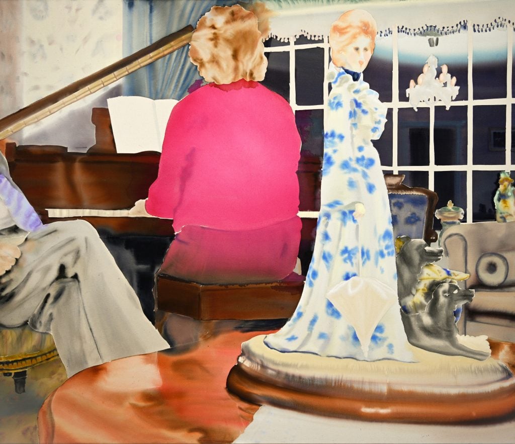 An interior with a woman with her back to the viewer playing the piano and a person sitting with only their crossed legs visible, and tabletop collectable doll in the foreground.