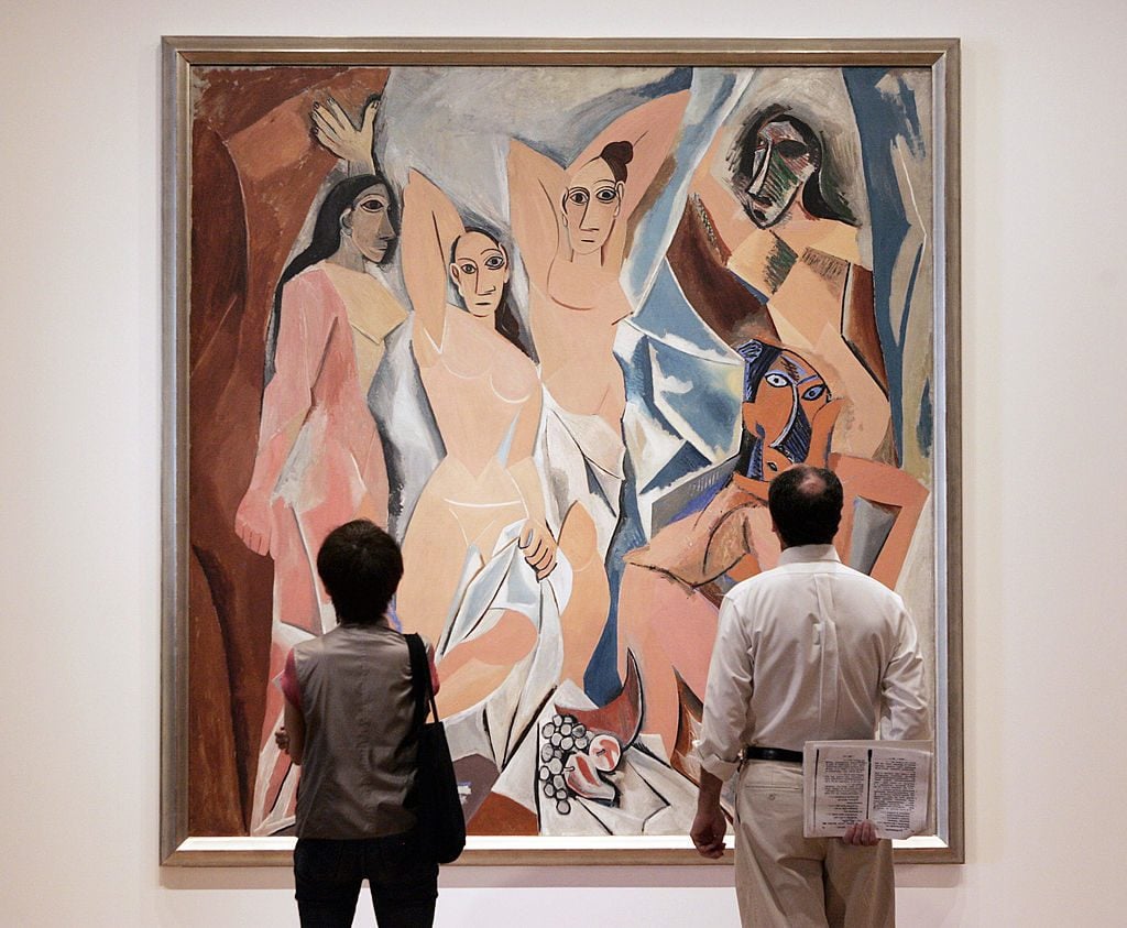 A man and woman stand in front of the cubist painting, in which five female figures are displayed in abstracted forms with tribal influence.
