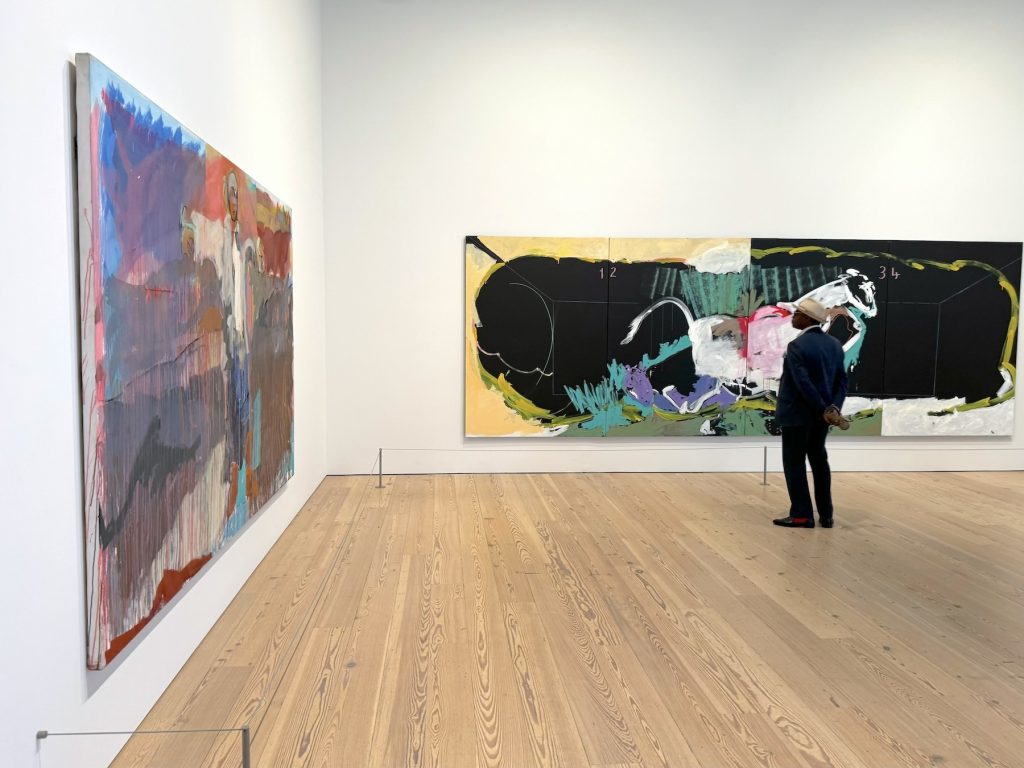 A man in an art gallery standing in front of a large abstract painting
