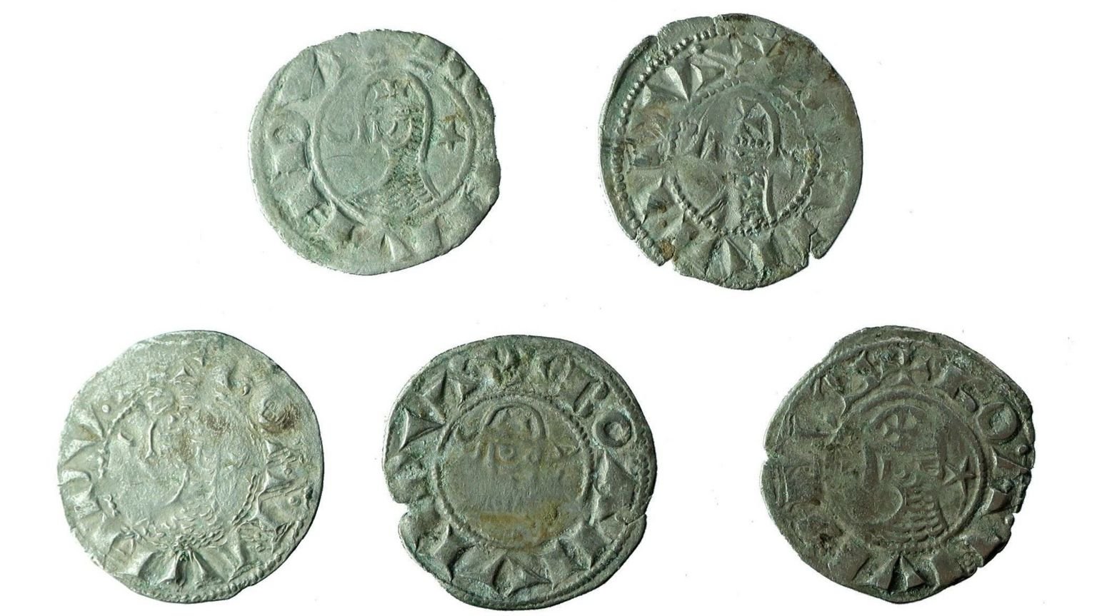 Five aged silver coins against a white background.