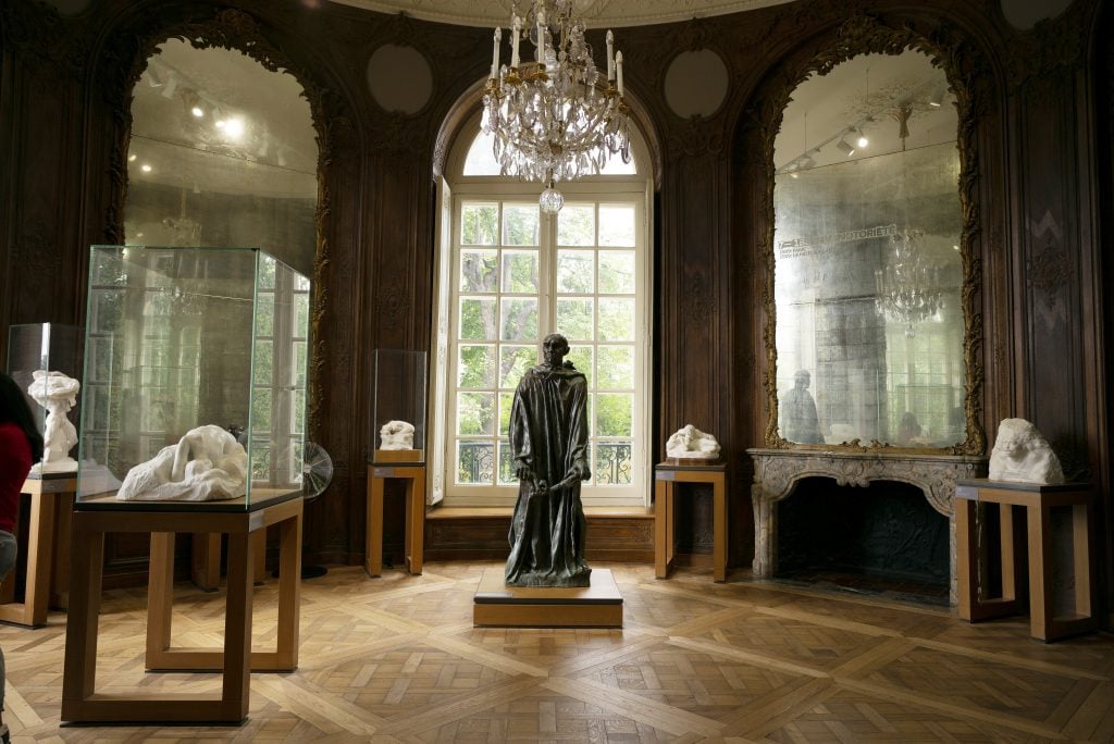 A room with a bronze statue installed against a large window.
