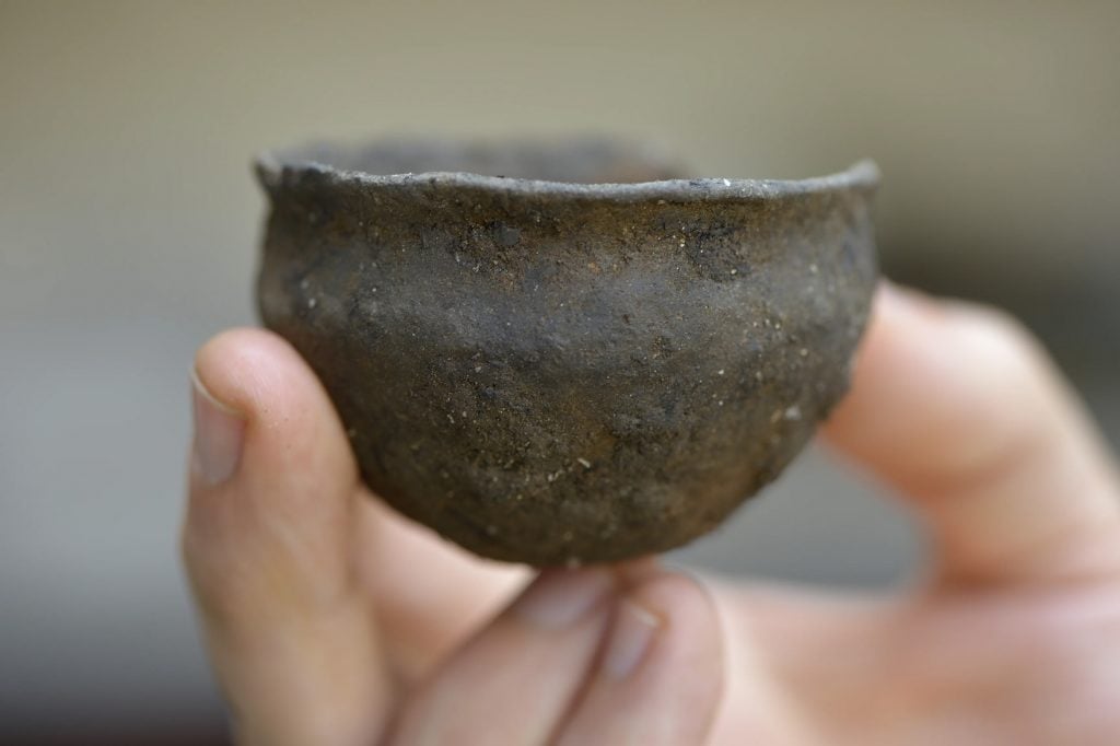 A hand holding an ancient bowl.