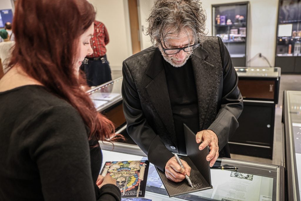 Author Neil Gaiman signs a book for a fan at a sale at Heritage Auctions.