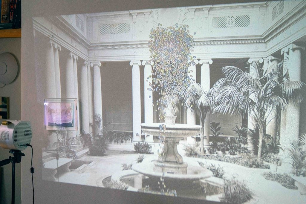 A large view of a projection, featuring an architectural background with a projection of a person on a bed, creating a juxtaposition of indoor and outdoor spaces.